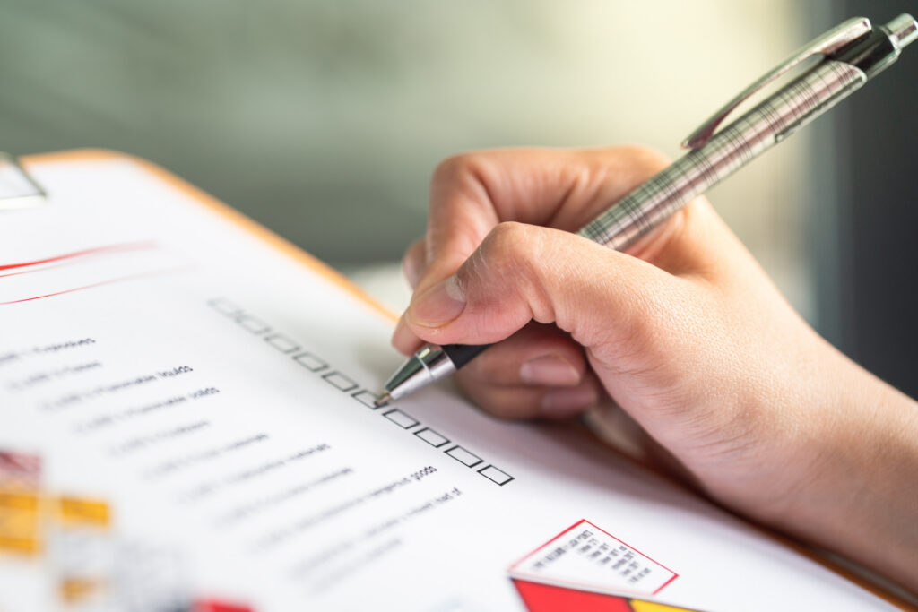 Hand ticking boxes on a printed inspection checklist during a packaging audit
