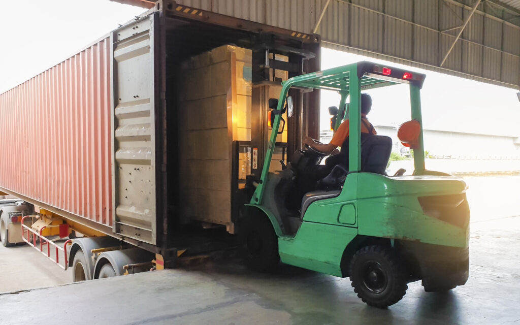 Forklift loading a pallet of goods into a shipping container for export