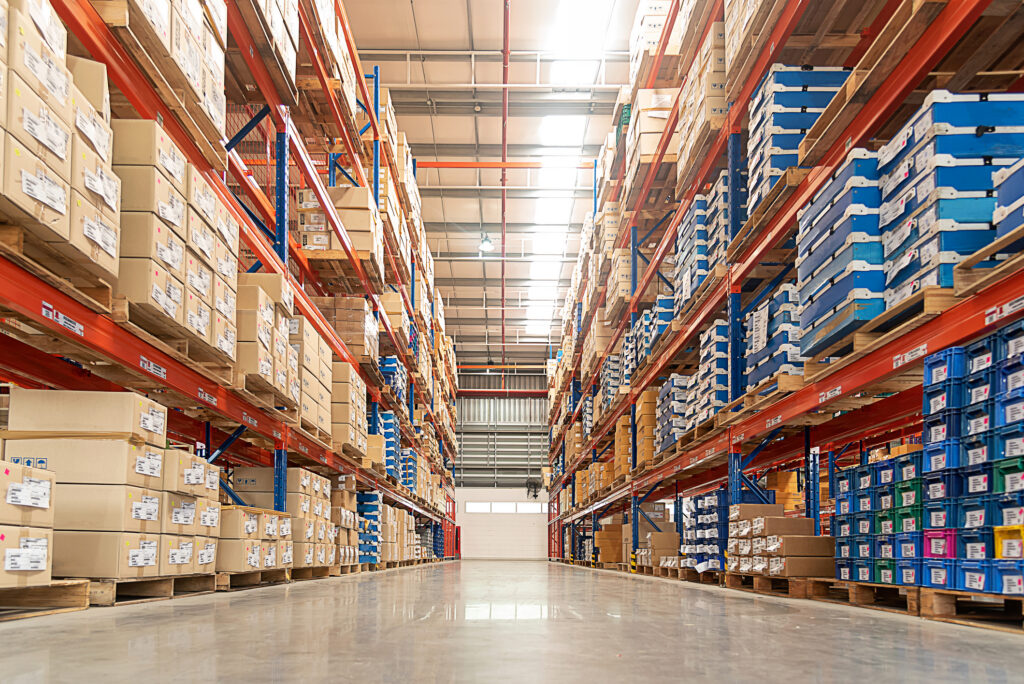 Warehouse aisle lined with pallet racking full of cartons and stacked crates